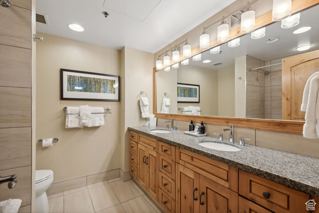 Bathroom with a tile shower, vanity, toilet, and tile patterned floors