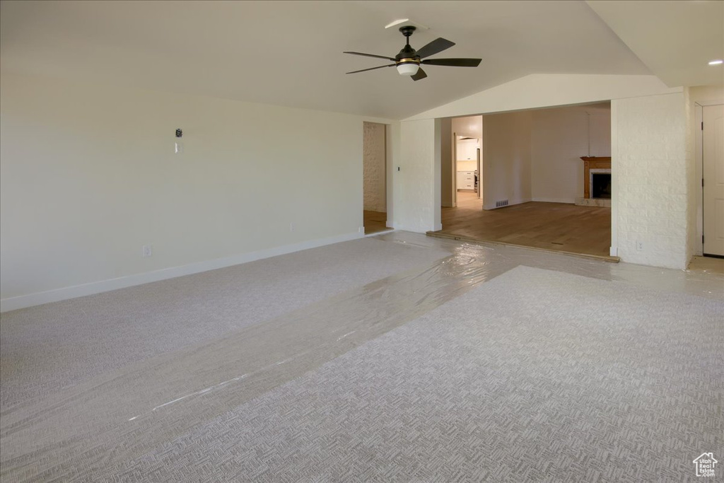 Unfurnished room featuring vaulted ceiling, light carpet, and ceiling fan