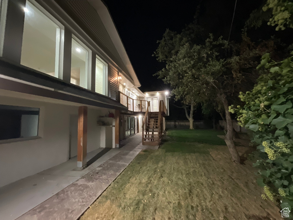 Property exterior at night with a yard and a patio