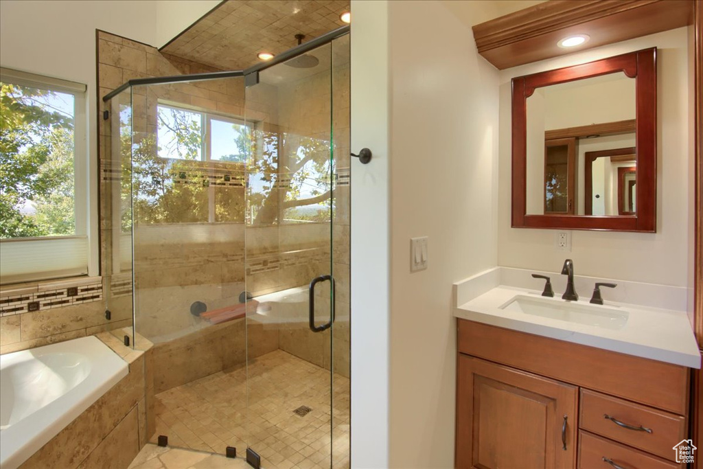 Bathroom featuring plus walk in shower, a wealth of natural light, and vanity