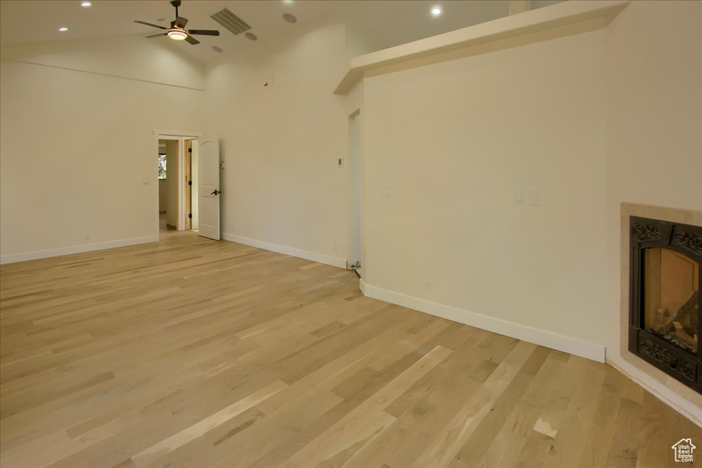 Unfurnished living room with ceiling fan, light hardwood / wood-style flooring, and high vaulted ceiling