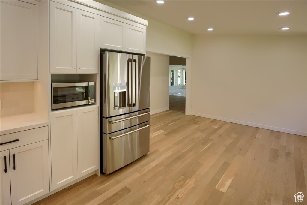 Kitchen featuring light wood-type flooring, white cabinetry, and stainless steel appliances