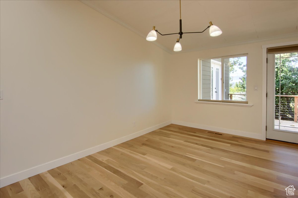 Empty room with plenty of natural light, hardwood / wood-style floors, and crown molding