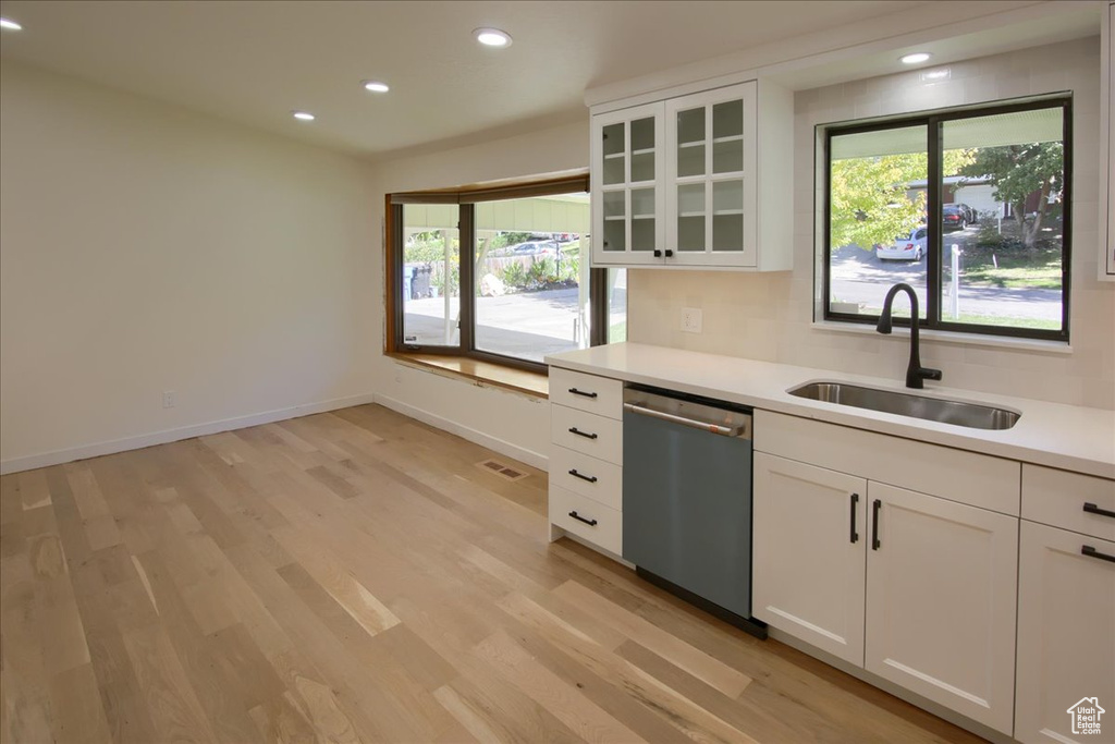 Kitchen featuring light wood-type flooring, dishwasher, white cabinetry, and sink