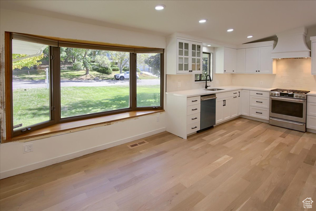 Kitchen featuring stainless steel appliances, white cabinetry, a healthy amount of sunlight, and sink