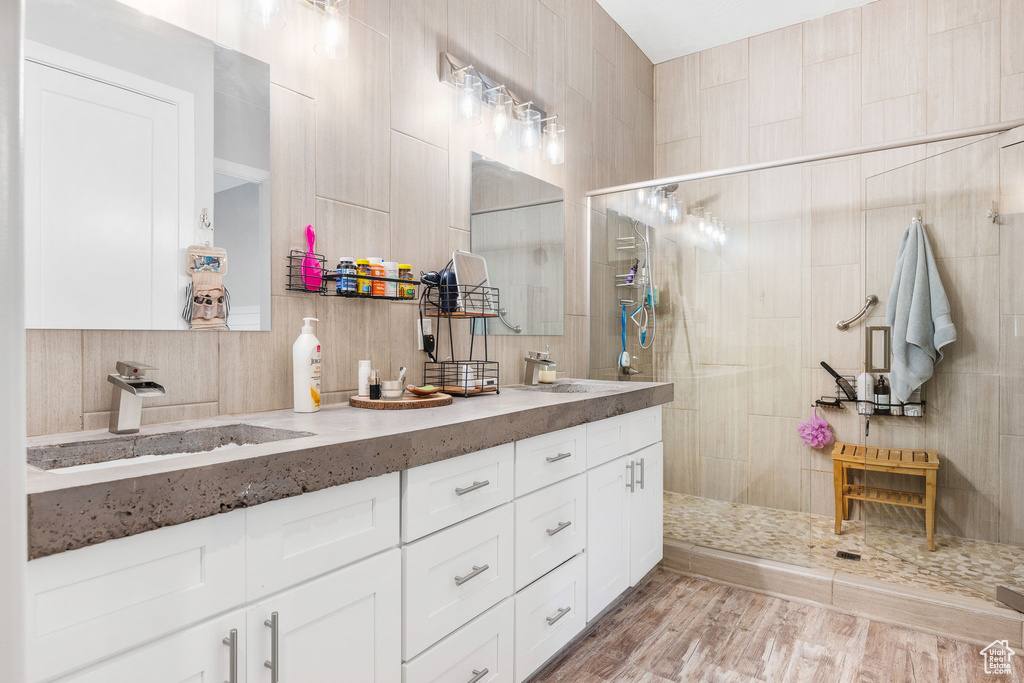 Bathroom featuring vanity, tile walls, hardwood / wood-style floors, and tiled shower