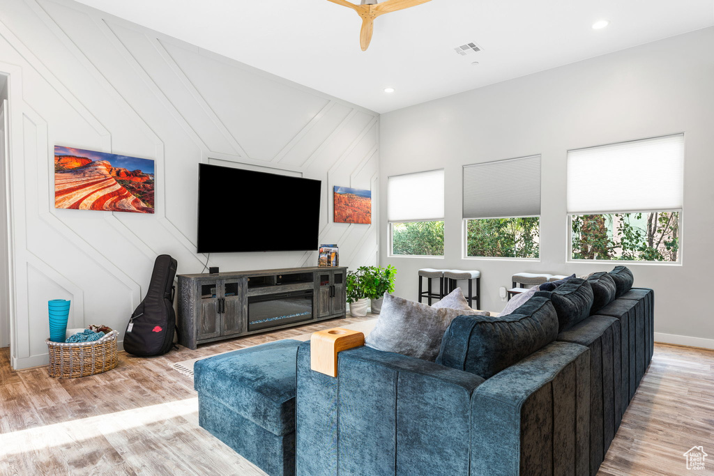 Living room featuring a wealth of natural light, wood-type flooring, and ceiling fan