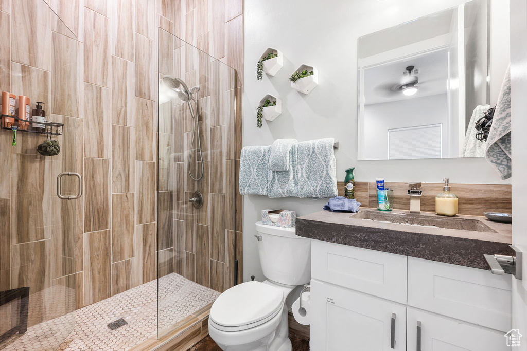 Bathroom with walk in shower, vanity, toilet, and ceiling fan