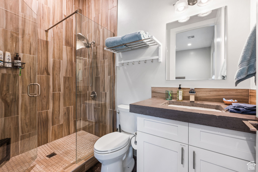 Bathroom featuring vanity, toilet, and an enclosed shower