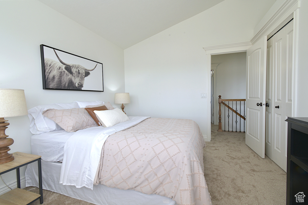 Bedroom with light carpet, vaulted ceiling, and a closet