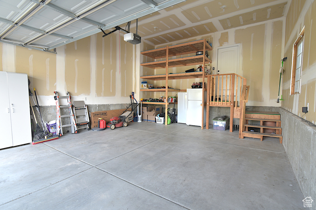 Garage with a garage door opener and white refrigerator