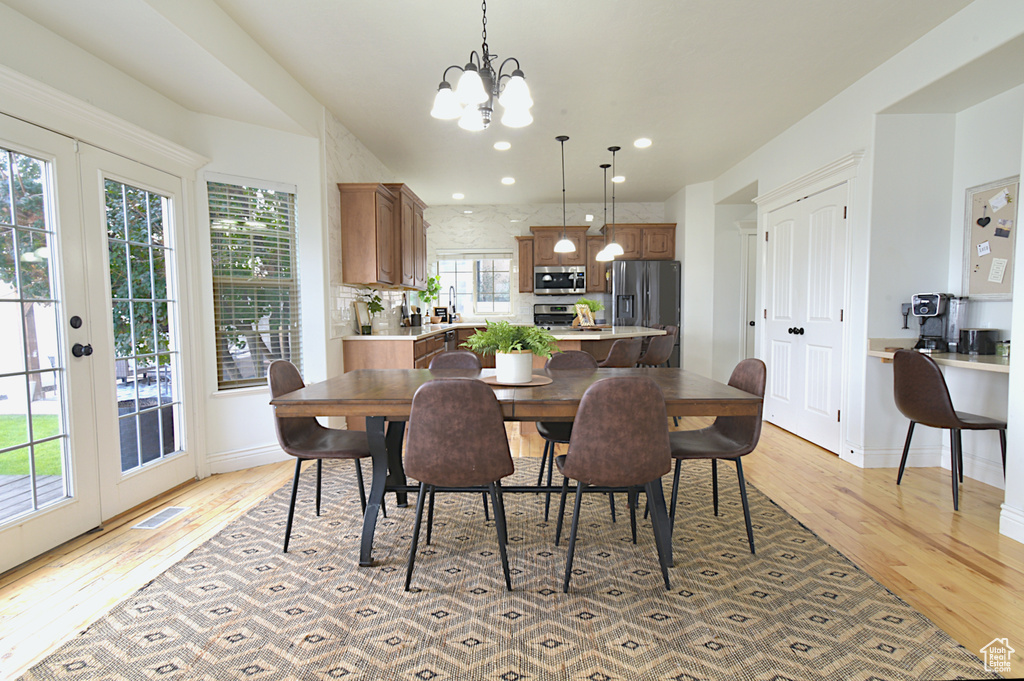 Dining area featuring french doors, light hardwood / wood-style flooring, a chandelier, and a healthy amount of sunlight