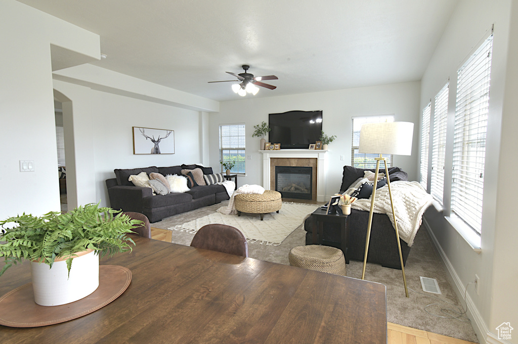 Living room with ceiling fan, a tile fireplace, and plenty of natural light