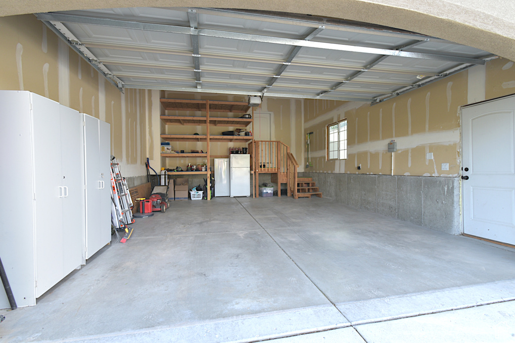 Garage with a garage door opener and white fridge