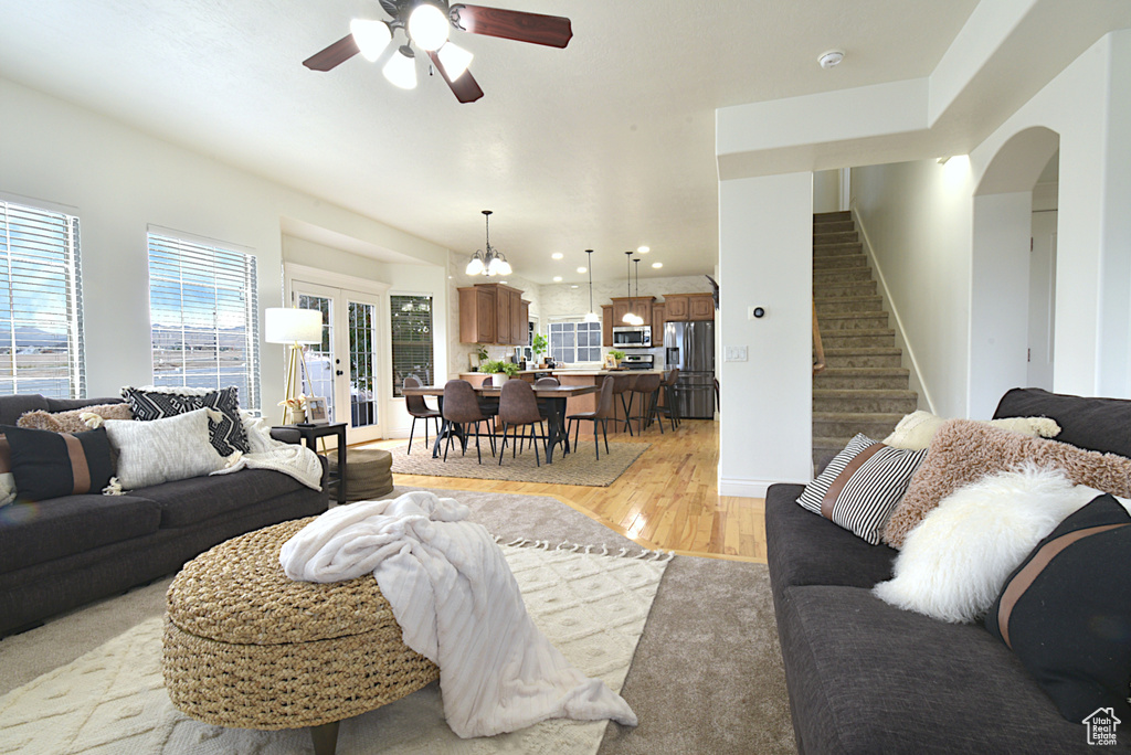 Living room featuring ceiling fan with notable chandelier and light hardwood / wood-style floors