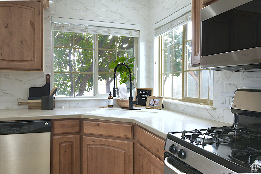 Kitchen featuring appliances with stainless steel finishes, backsplash, and sink