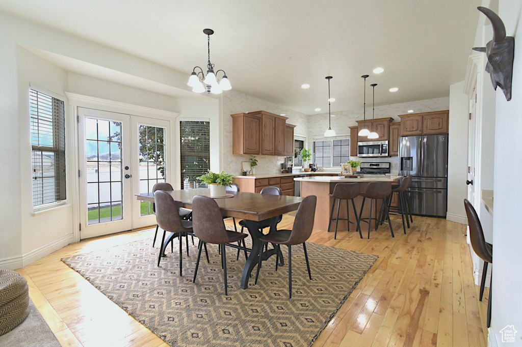 Dining area with light hardwood / wood-style flooring, an inviting chandelier, and french doors