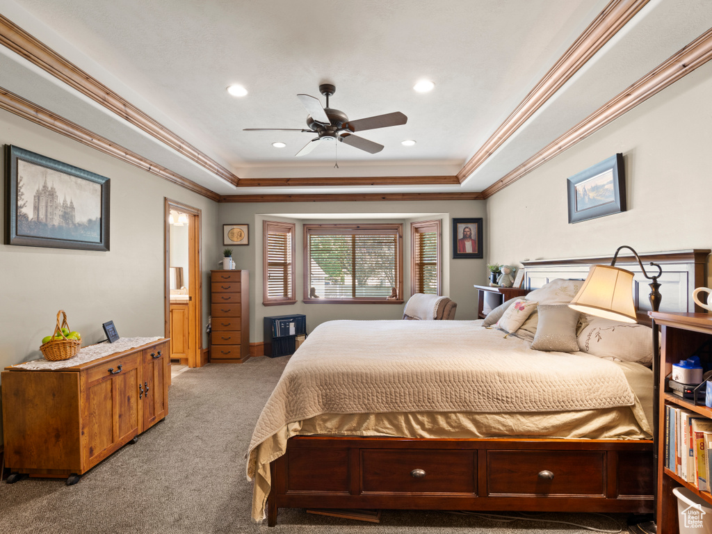 Carpeted bedroom featuring crown molding, ceiling fan, and a raised ceiling