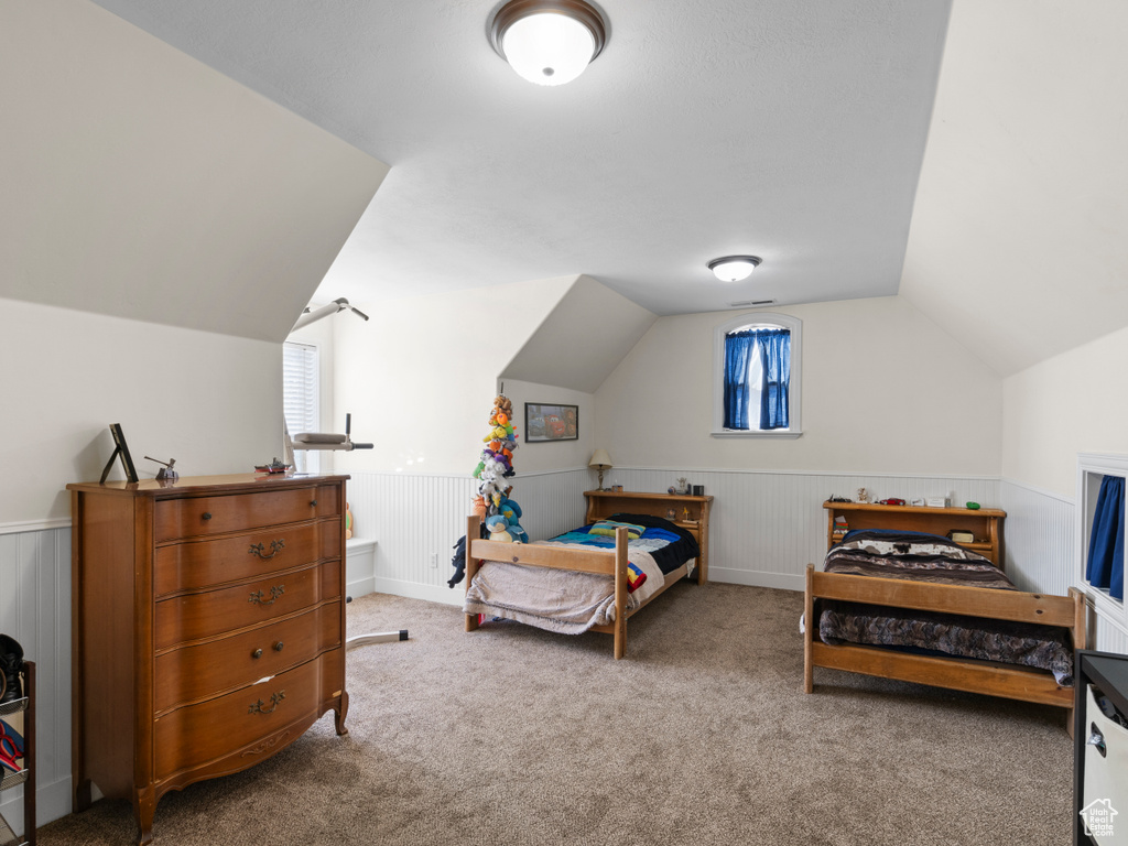 Bedroom featuring vaulted ceiling, multiple windows, and carpet floors