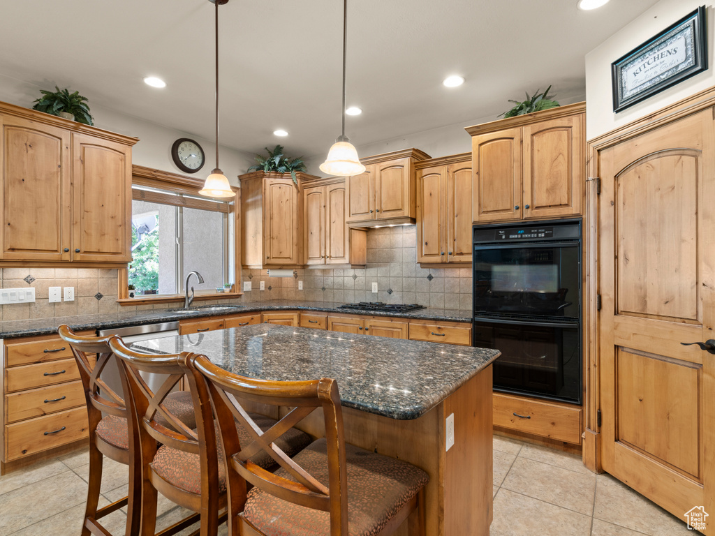 Kitchen featuring pendant lighting, sink, a kitchen island, a kitchen breakfast bar, and gas stovetop