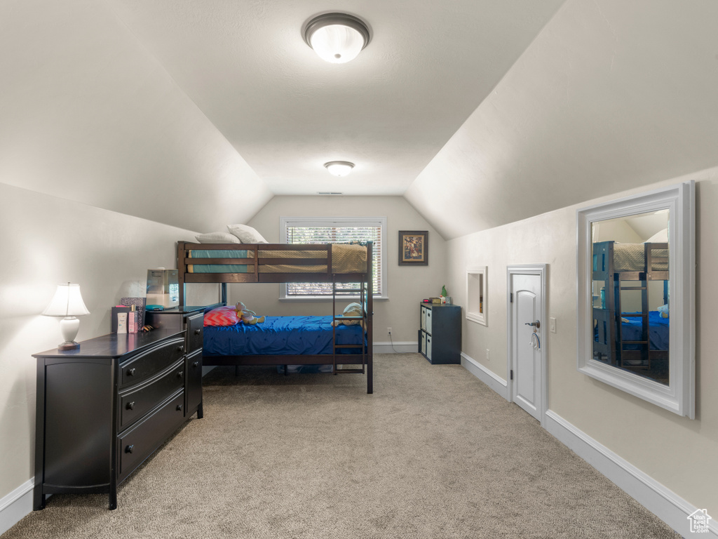 Carpeted bedroom featuring vaulted ceiling