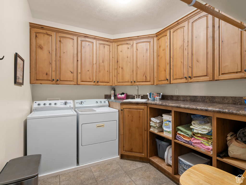 Washroom featuring cabinets, light tile patterned flooring, separate washer and dryer, and sink