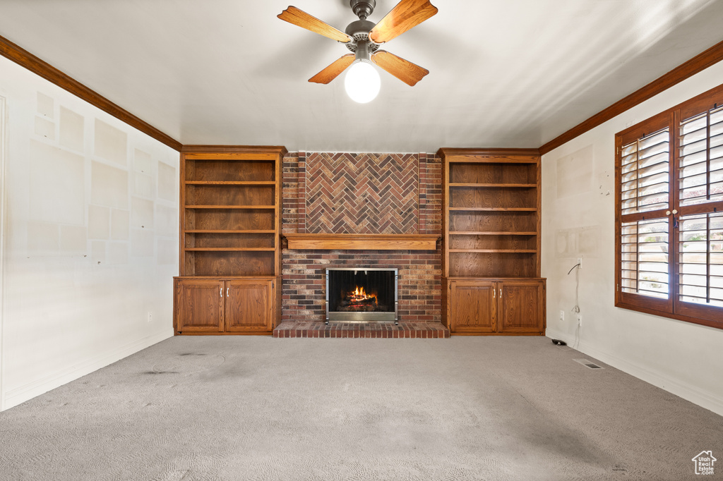 Unfurnished living room with ceiling fan, carpet floors, a brick fireplace, and ornamental molding