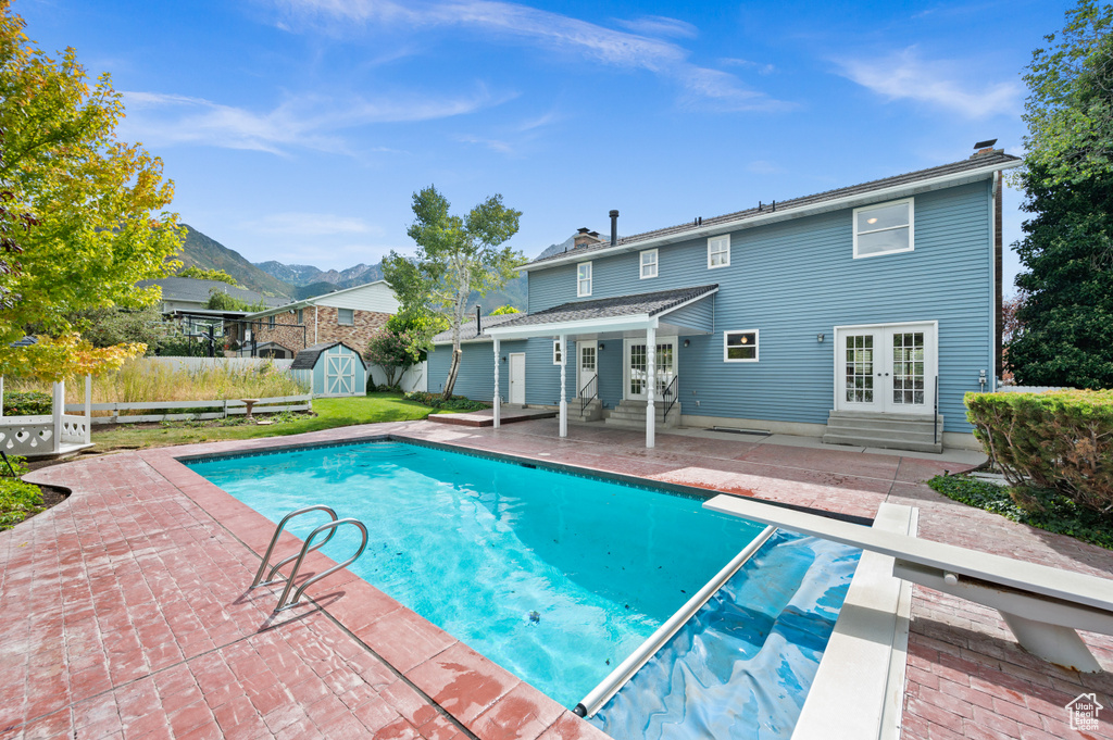 View of pool featuring a mountain view, a storage unit, a patio area, a diving board, and french doors