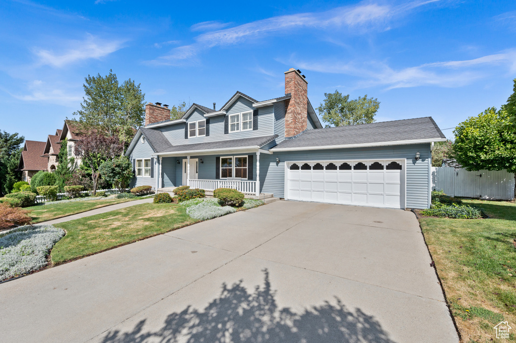 View of front of home with a front yard, a garage, and a porch