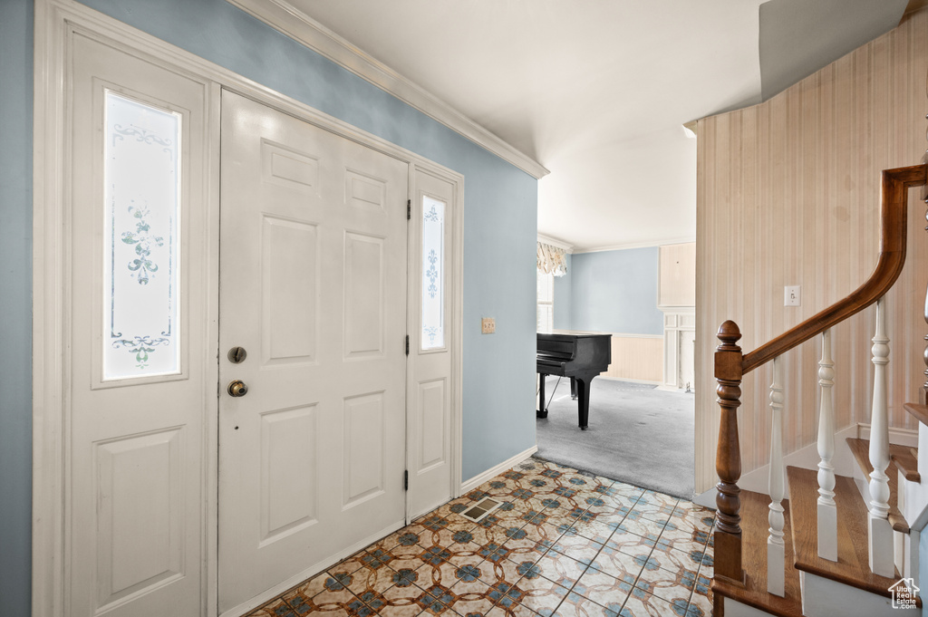 Carpeted entryway with ornamental molding