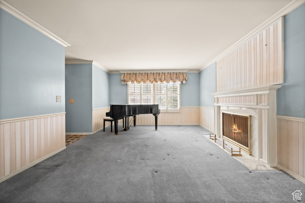 Unfurnished living room featuring ornamental molding, wooden walls, a premium fireplace, and light colored carpet