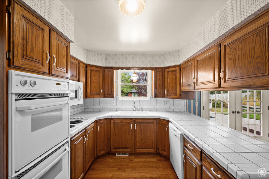 Kitchen with tile countertops, sink, white appliances, and a wealth of natural light