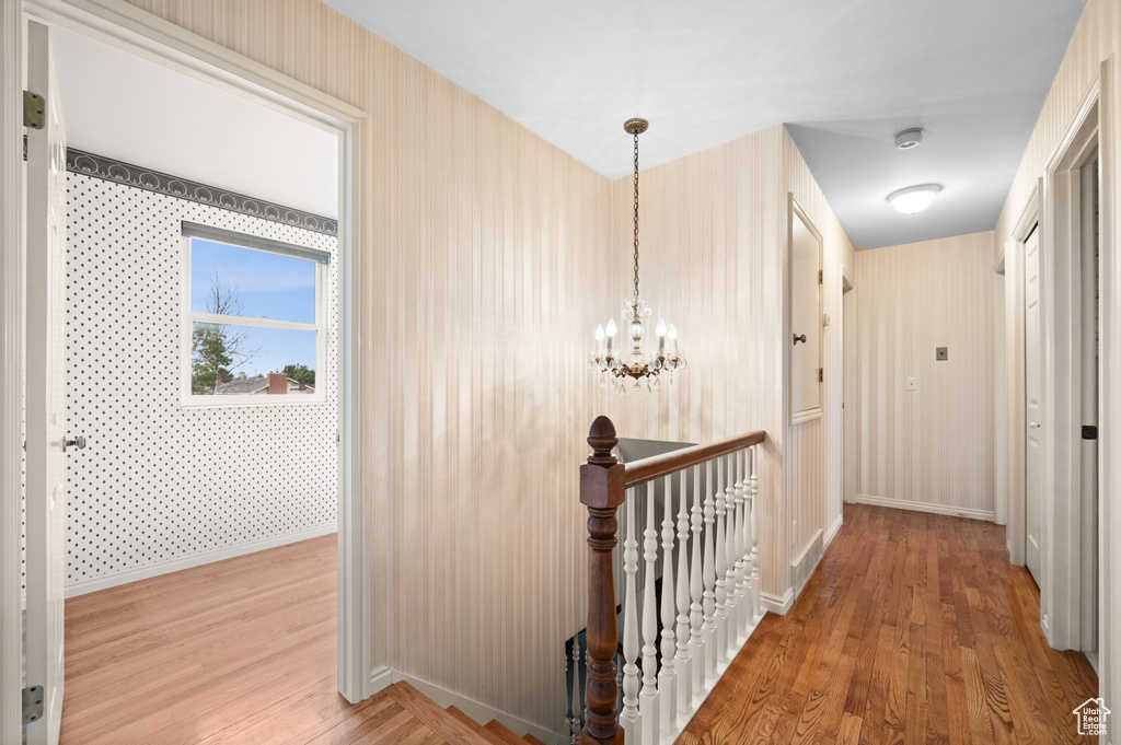 Hallway featuring a notable chandelier and wood-type flooring