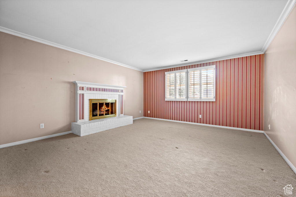 Unfurnished living room featuring crown molding, carpet, and a brick fireplace