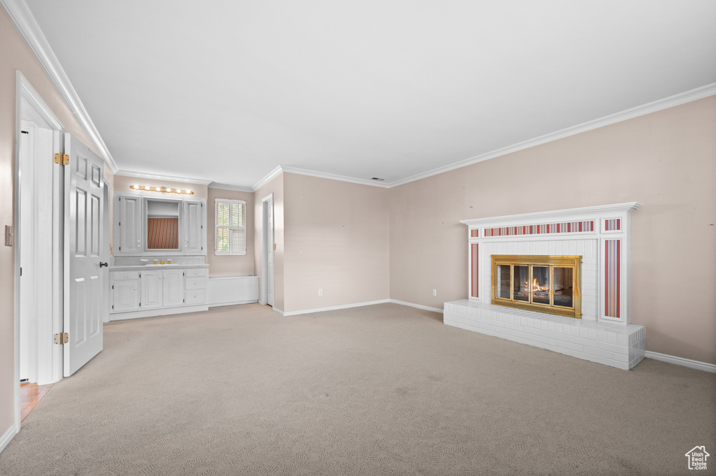 Unfurnished living room with a fireplace, ornamental molding, and light colored carpet