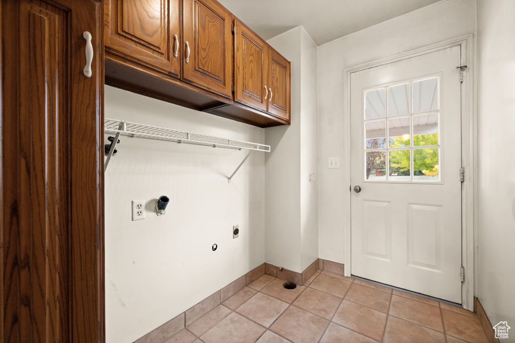 Laundry area featuring light tile patterned flooring, electric dryer hookup, and cabinets