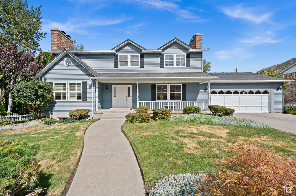 Front facade featuring a porch, a garage, and a front yard