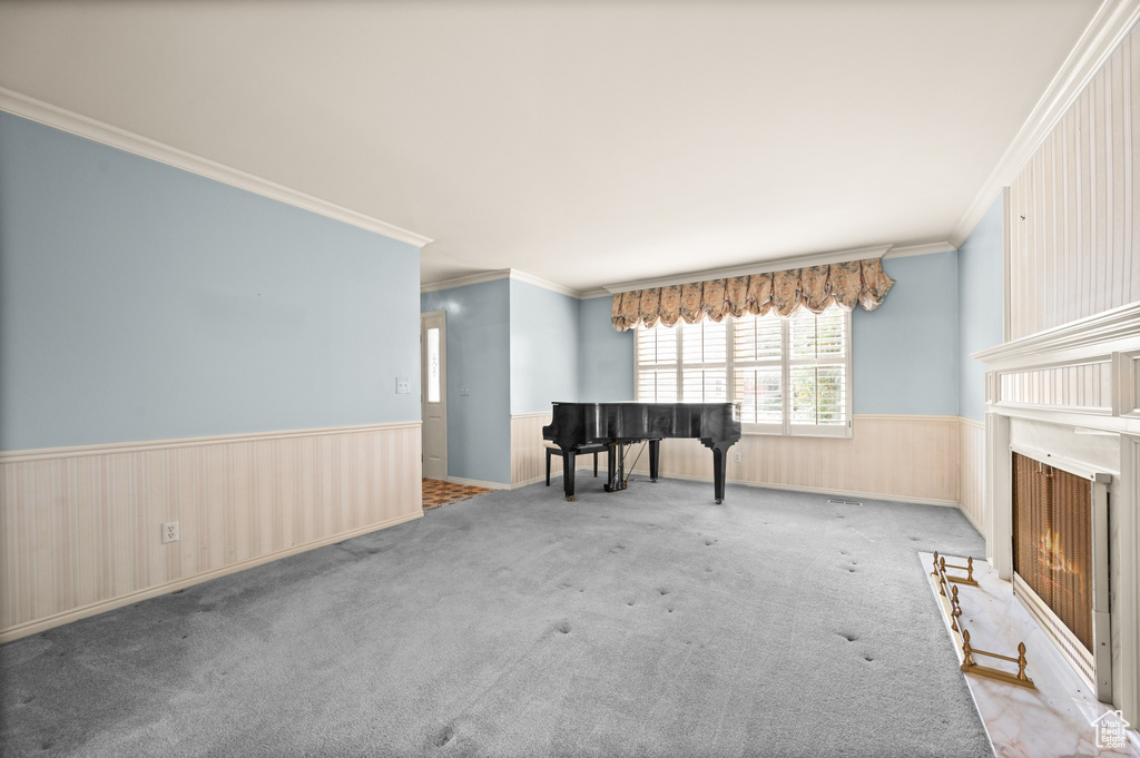 Empty room featuring ornamental molding, wooden walls, and light colored carpet