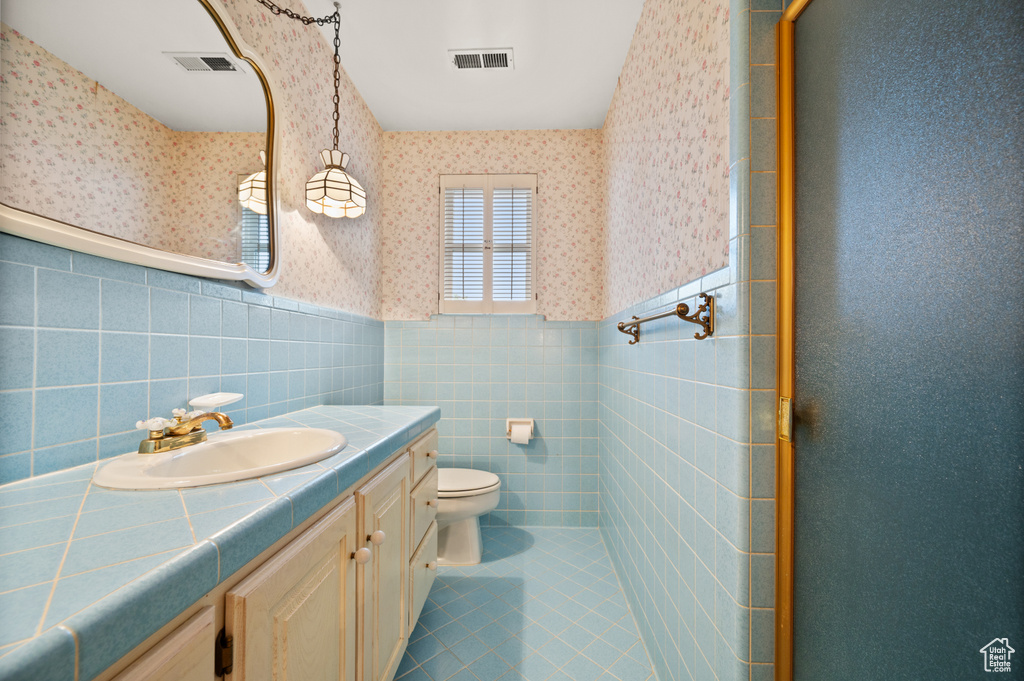 Bathroom featuring vanity, tile walls, tile patterned flooring, and toilet