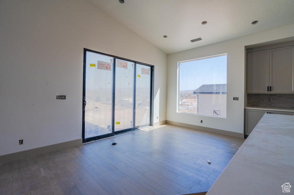 Interior space featuring a textured ceiling, light wood-type flooring, and vaulted ceiling