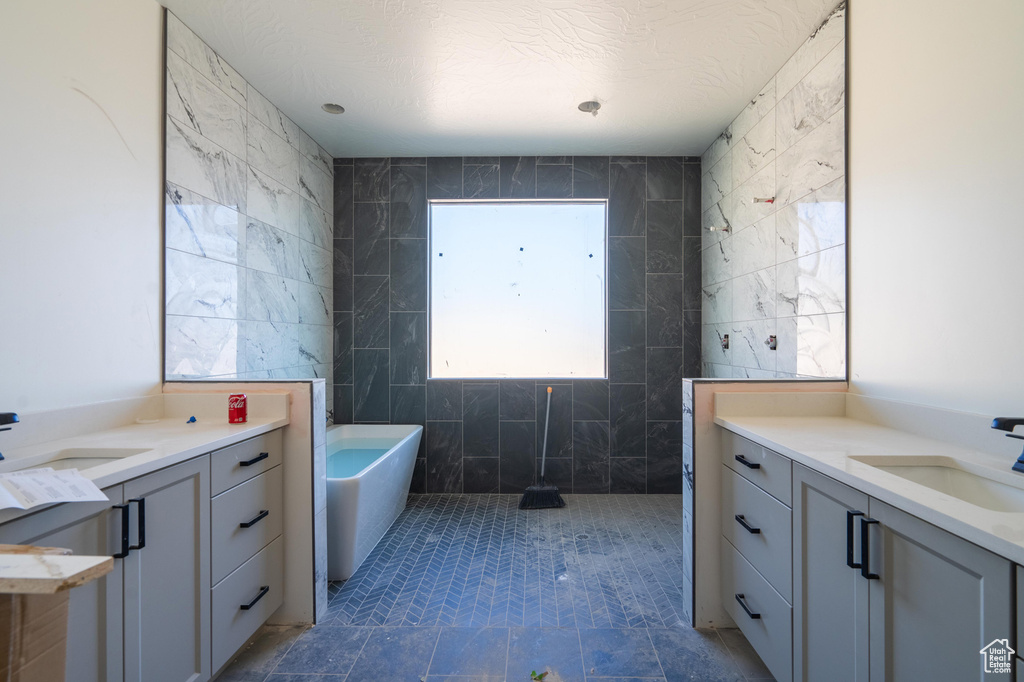 Bathroom featuring tile walls, a bathing tub, and vanity