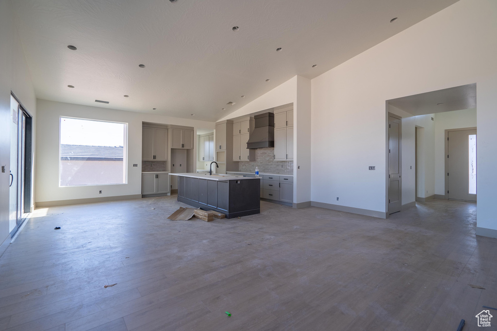 Kitchen featuring premium range hood, sink, vaulted ceiling, a kitchen island with sink, and hardwood / wood-style floors