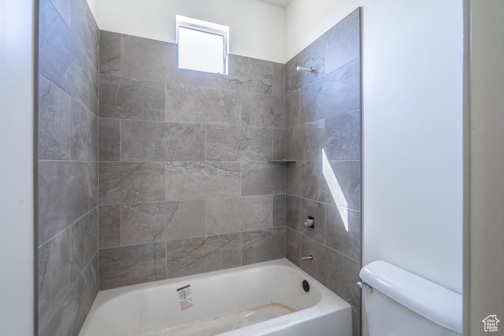 Bathroom featuring tiled shower / bath combo and toilet