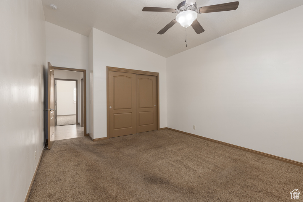 Unfurnished bedroom with lofted ceiling, carpet floors, a closet, and ceiling fan