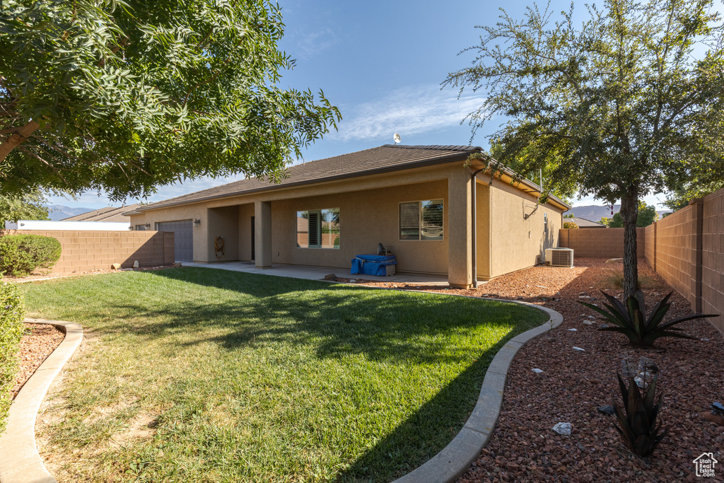 Back of property with a patio, central AC unit, and a lawn