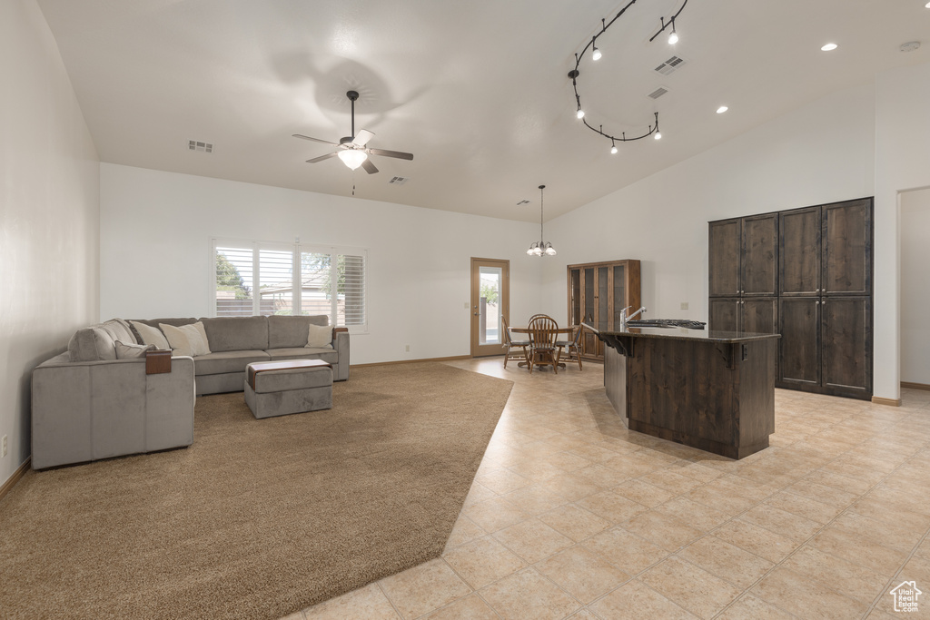 Living room featuring high vaulted ceiling and ceiling fan with notable chandelier