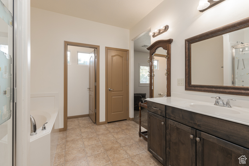 Bathroom featuring vanity, a bath, and a healthy amount of sunlight