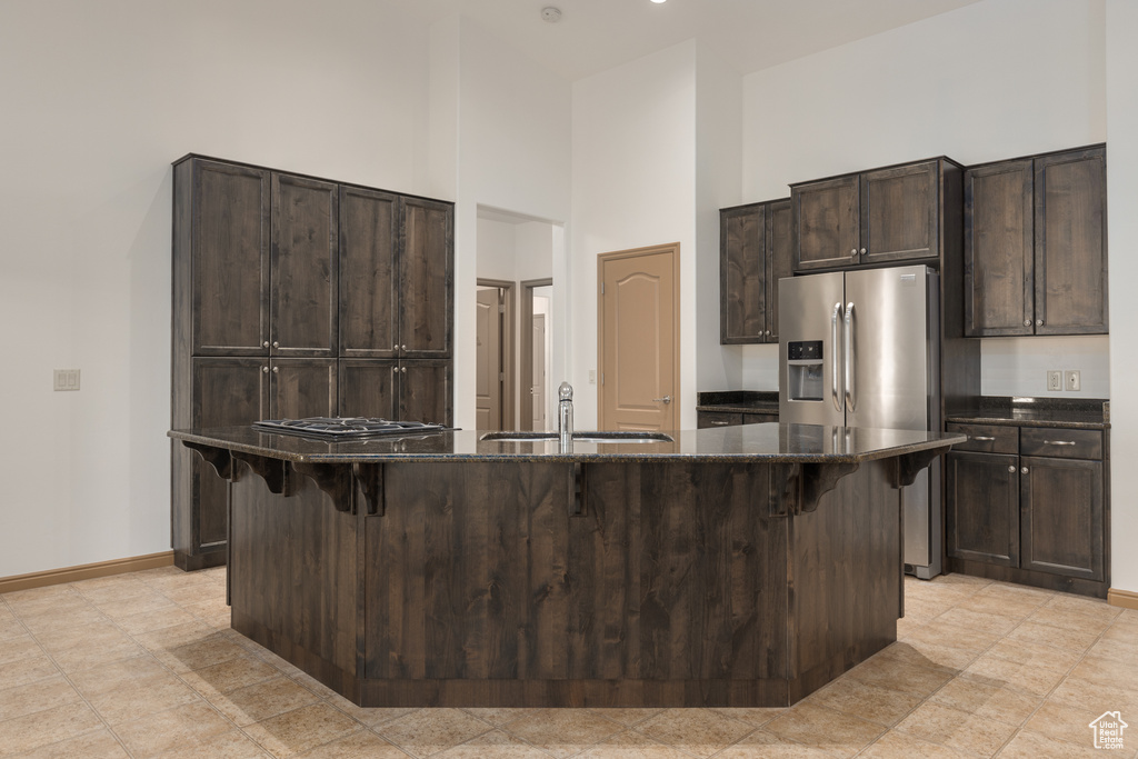 Kitchen featuring a breakfast bar area, sink, a kitchen island with sink, and a high ceiling