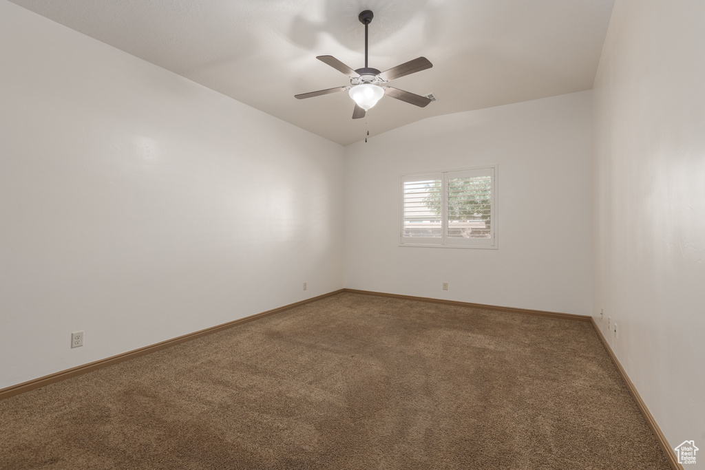 Empty room with ceiling fan, lofted ceiling, and carpet floors