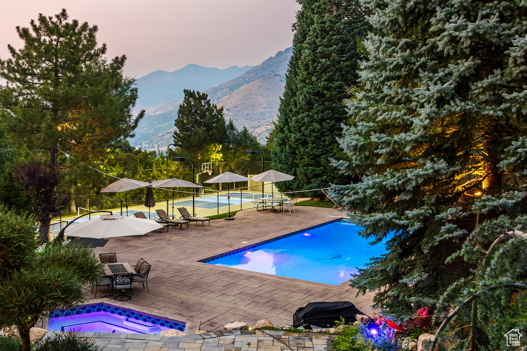 Pool at dusk with a mountain view and a patio